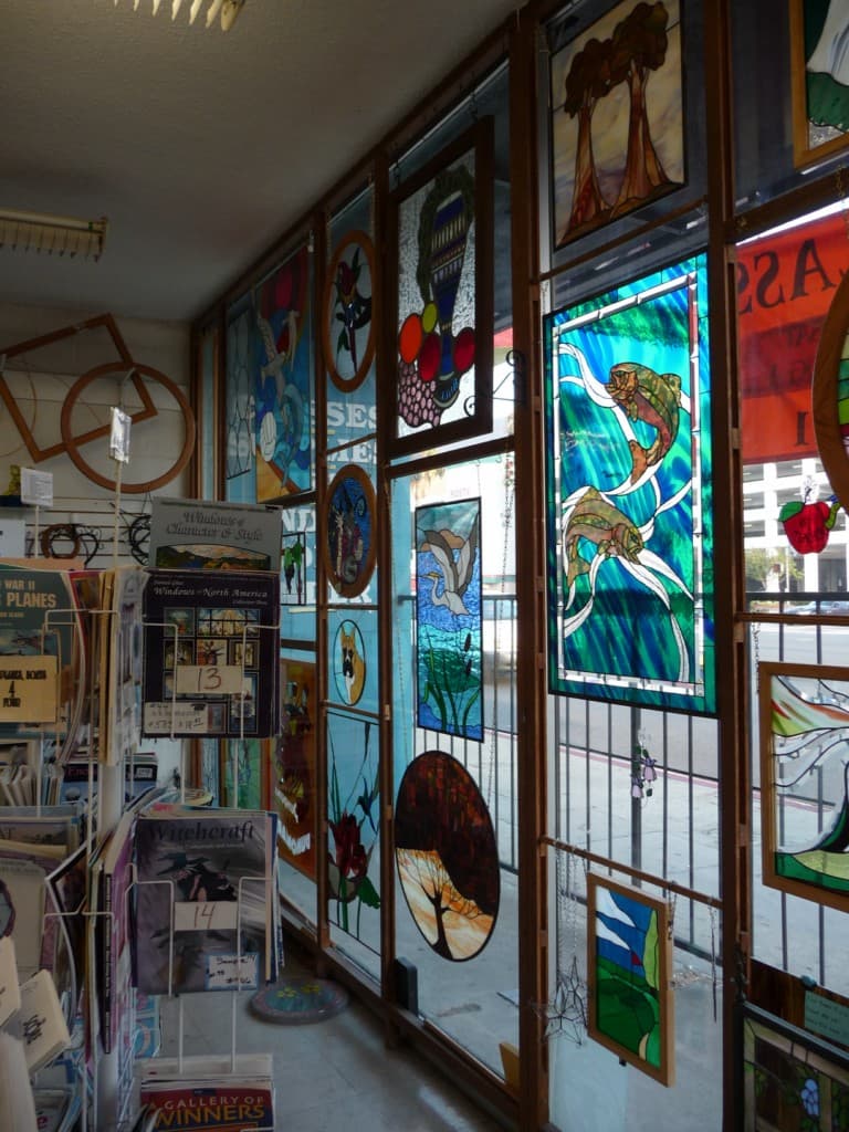 Studio display wall featuring tools, frits, and finished glass pieces